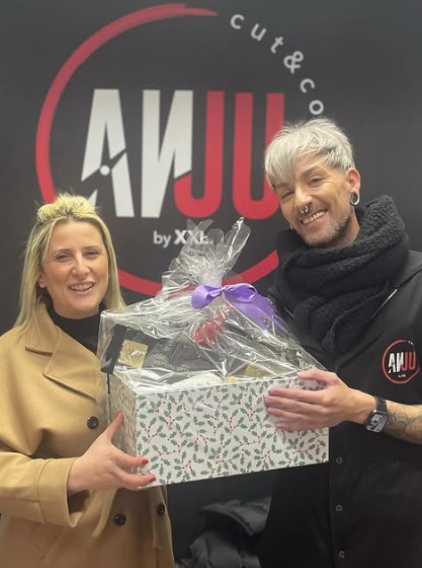 Cliente y profesional de Anju Peluqueros con regalo en el salón